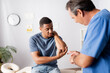 © LIGHTFIELD STUDIOS - injured african american man showing elbow to doctor in clinic