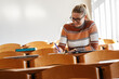 © BalanceFormCreative - Young blond hair female student taking a test in university classroom.