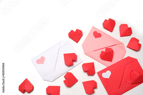 Red, pink, white paper envelopes with colored hearts, surrounded by several handmade red 3D paper hearts on white background isolated copy space. Love, Valentine's, mother's, women's day concept 