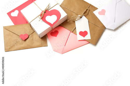 Red, pink, white paper envelopes with colored hearts, white gift box with red label in a heart form, envelope from craft paper with red heart, white gift box with red label in a heart form on white 