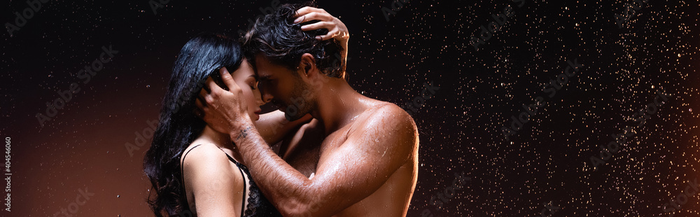 side view of couple embracing and kissing under rain on dark background, banner - obrazy, fototapety, plakaty 