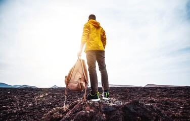 Wall Mural - Successful man hiking mountains - Hiker with backpack climbing on the top of the rock at sunset - Success, sport and motivational concept