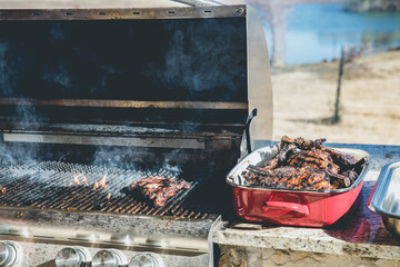 Closeup of steaks on a grill with well-done steaks on a serving platter