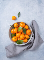 sweet and juicy tangerines in a gray bowl on a blue background