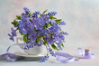 A bouquet of blue flowers of periwinkle, muscari and violets in a cup on a decorative background. Color of the year 2022.