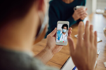 Wall Mural - Close-up of a man greeting his doctor during video call over smart phone.