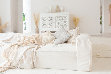  Cozy interior of a bright Balinese-style apartment with white walls, bamboo chair, big white sofa and decorations