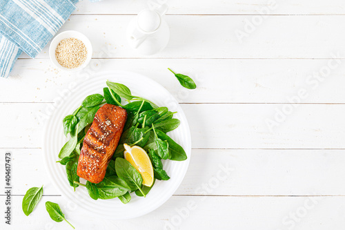 Obraz Dibond Salmon fish fillet grilled and fresh spinach salad on plate for lunch. Top view