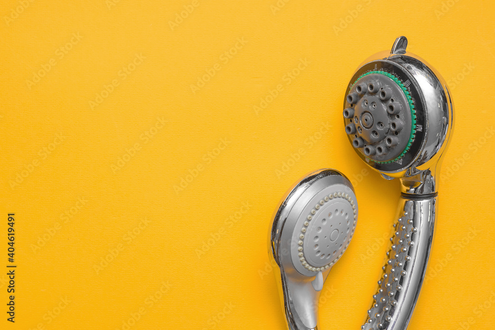 Two different old shower heads on the yellow flat lay background with copy space. Replacement of shower head concept. - obrazy, fototapety, plakaty 