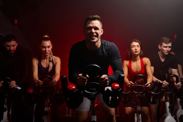 sportsman diligently riding an exercise bike in gym, the guy is exercising on a stationary bike