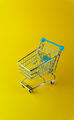 Vertical top view of an empty shopping cart isolated on yellow background with copyspace