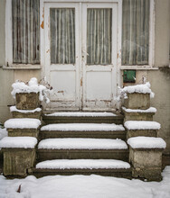 An Old White Entrance Door With Stairs Covered By The Snow