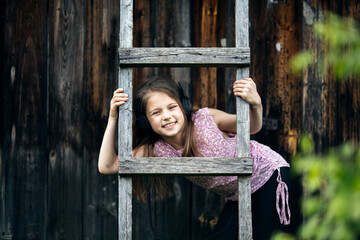 Wall Mural - Little girl with headphones in the village, outdoors.