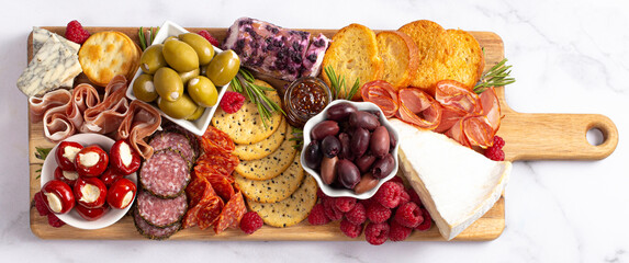 A Savoury Charcuterie Board Covered in Meats Olives Peppers Berries and Cheese