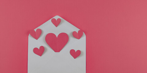 Wall Mural - Envelope and hearts.

Envelope and crumbling hearts on the left on a pink background with space for text on the right, top view close-up.