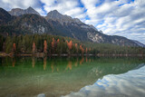 Fototapeta Sypialnia - Esmerald lake and mountains in autumn with a cloudy sky and yellow trees