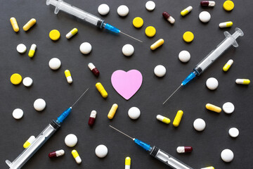 Heart treatment. Drugs harm to heart. Pink heart surrounded by many drugs, syringes and pills. Flat lay. Top view 