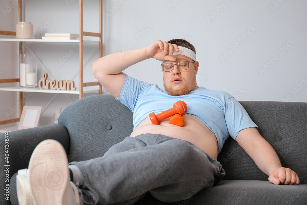 Exhausted overweight man after training at home. Weight loss concept