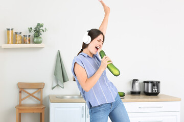 Canvas Print - Beautiful young woman with headphones in kitchen