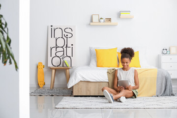 Wall Mural - Teenage African-American girl with tablet computer at home