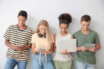 Wall Mural - Teenagers with different devices on light background