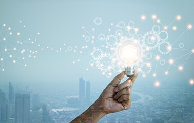 Leinwandbilder - Double exposure. New ideas. Innovation and creativity. Technology and development. Businessman hand holding light bulb and cog wheel on city background. Blue tone.