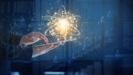 Leinwandbilder - Businessman holding and using a digital tablet device with glowing light bulb on network connectivity, Science, Innovation, Idea and creativity concept.