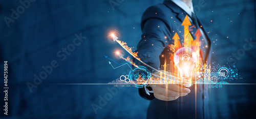Obraz Dibond Hot business growth. Creativity of marketing, Businessman holding light bulb and analyzing sales data and economic growth graph chart. Business strategy, financial and banking. Digital marketing.