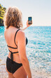 © andrey gonchar - A slender blonde woman in a black bikini swimsuit is photographed on the seashore