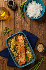 Wall Mural - Asian dish. Fried salmon with rice and vegetables. Sprinkled with sesame seeds.