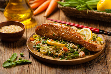 Wall Mural - Asian dish. Fried salmon with rice and vegetables. Sprinkled with sesame seeds.