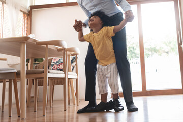 Playful African American Dad and his cute little son walking on the floor