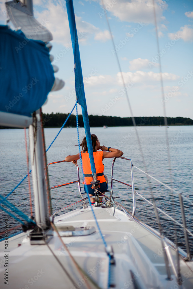 Chłopiec siedzący na dziobie jachtu podczas rejsu po jeziorze Jeziorak  - obrazy, fototapety, plakaty 