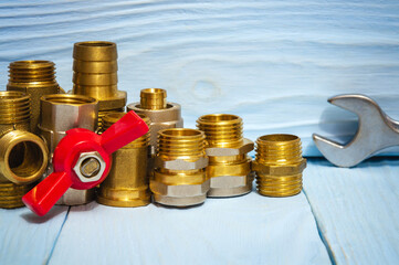 Wall Mural - Brass fittings and wrench on blue boards close up. Plumbing repair idea