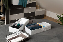 Vertical Storage Of Clothing. Sorted Clothes In Baskets And Shelves In A Modern Bedromm. Cleaning Concept.