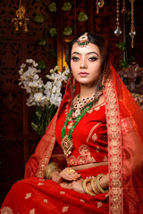 Wall Mural - Magnificent young Indian bride in luxurious dress and precious jewellery is sitting in a chair in a luxury apartment. Classic vintage interior. Wedding fashion.