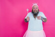 Funny man dancing and having fun wearing  a ballet outfit. Happy princess on a pink colored background