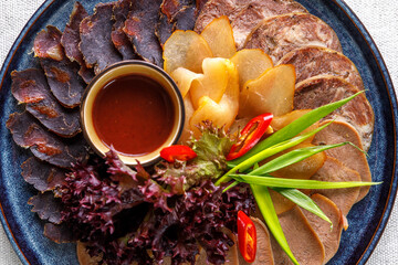 Wall Mural - Sliced cold cuts with lettuce, hot pepper, green onions and sauce on a platter close-up.