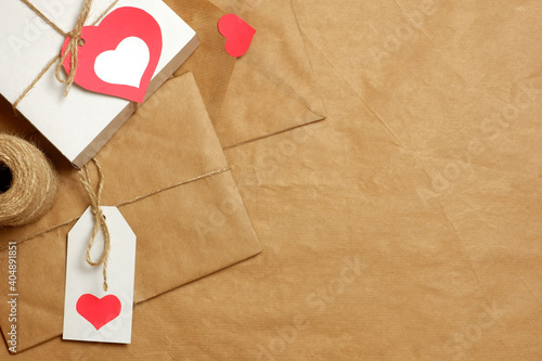 Gifts and envelope wrapped in brown craft paper, tied with twine with bows and labels, hearts and coil of twine on craft paper background. Love, Valentine's, mother's, women's day, romantic concept 