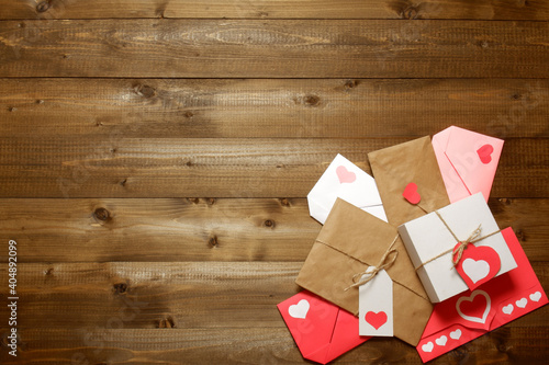 Gifts and envelopes, colored and wrapped in brown craft paper, tied with twine with bows and labels, hearts on brown wooden boards. Love, Valentine's, women's day, relations, romantic template 