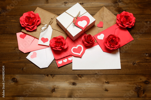 Love, Valentine's, women's day, relations, romantic design. Gifts, love letters, colored and wrapped in brown craft paper, tied with twine with bows, labels, 3D handmade paper roses on wooden planks 