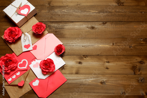 Gifts and envelopes, colored and wrapped in brown craft paper, tied with twine with bows and labels, hearts and roses on wooden planks background. Love, Valentine's, women's day, romantic concept 