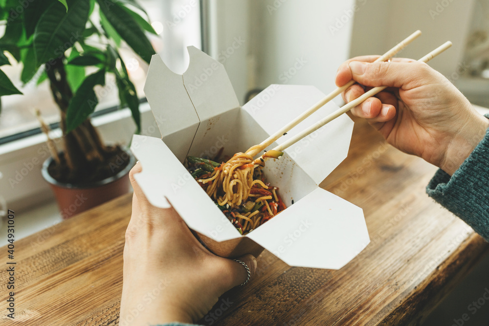 Close-up of noodles in a box. Takeaway food. Person eats food with chopsticks. - obrazy, fototapety, plakaty 