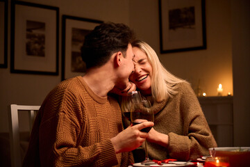 happy young couple in love hugging, laughing, drinking wine, enjoying talking, having fun together c