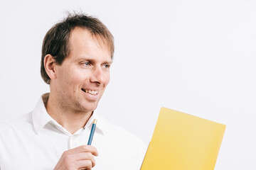 Young man looking aside while holding a yellow folder and a blue pen