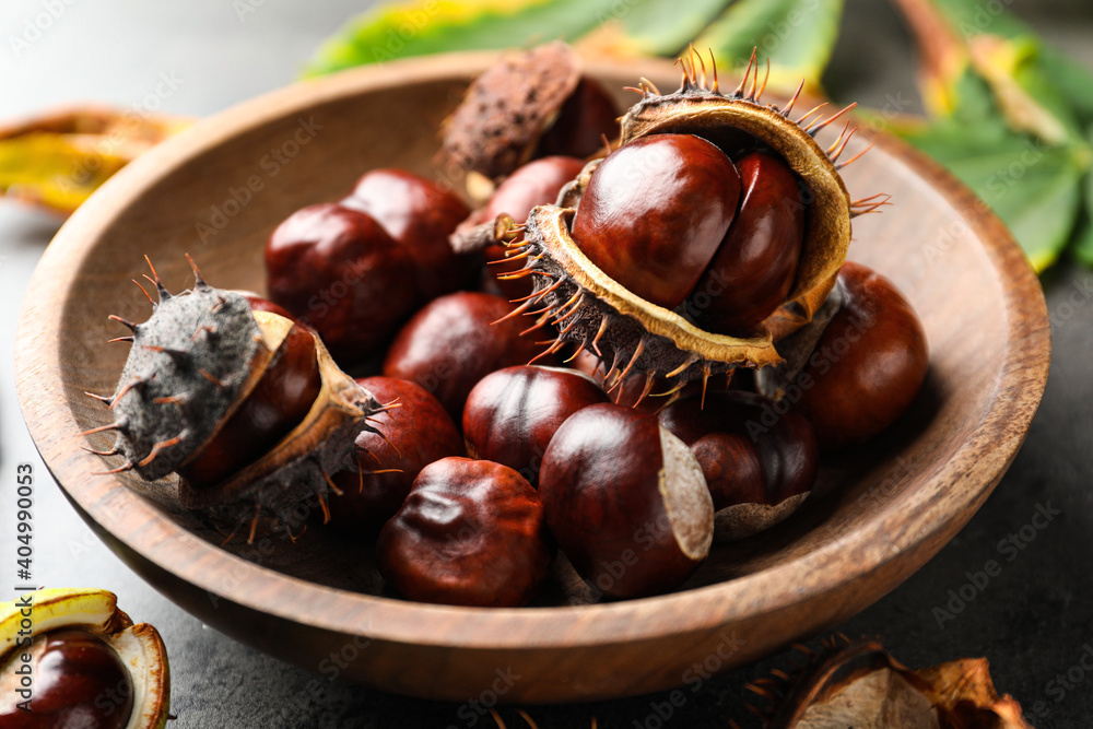 Horse chestnuts in wooden bowl on table, closeup view - obrazy, fototapety, plakaty 