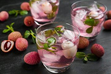 Delicious lychee cocktails with mint and fresh fruits on black table