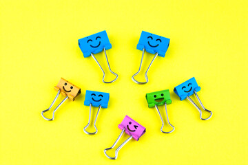 Smile colorful binder clips isolated on yellow