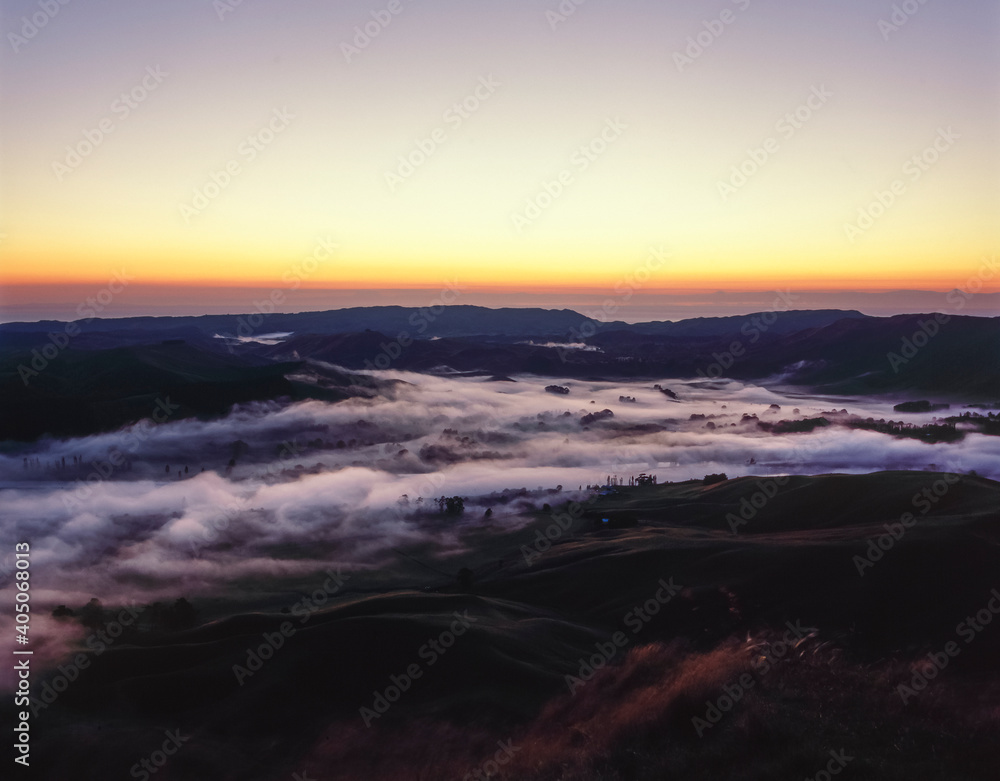 Laying Rising Main Sun rising over Hawkes Bay, New Zealand - low laying mist covering ...