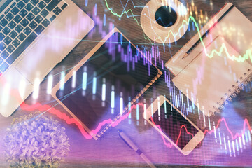 Double exposure of forex chart hologram over desktop with phone. Top view. Mobile trade platform concept.